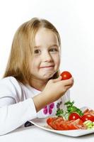 jolie petite fille avec une assiette de légumes frais photo