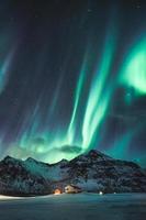 aurores boréales, aurores boréales avec des étoiles qui brillent sur une montagne enneigée dans le ciel nocturne en hiver sur les îles Lofoten photo