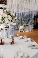 le présidium des jeunes mariés dans la salle de banquet du restaurant est décoré de bougies et de plantes vertes photo