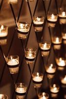 des bougies brûlent dans des verres sur l'arche de mariage photo