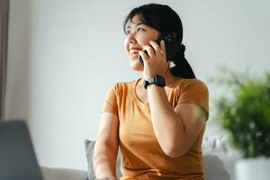 content femme parlant avec téléphone intelligent et en utilisant portable à Accueil Bureau ou lieu de travail. photo