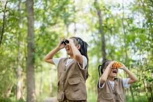 content peu asiatique les filles à la recherche devant et souriant enfant avec le jumelles dans le parc. Voyage et aventure concept. liberté, vacances photo