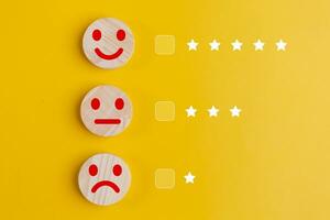 client Commentaires concept. en bois boutons avec smiley visages sur une Jaune Contexte photo