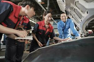 asiatique Masculin professionnel automobile superviseur conseille et inspecte une mécanicien ouvrier femme à propos liquide moteur pétrole à voiture garage, un service entretien, et réparer spécialiste métiers auto industrie. photo