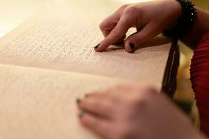 fermer de une femme main en train de lire une braille livre photo