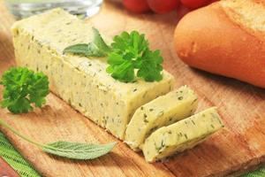 bâton de beurre aux herbes fraîches sur une planche à découper photo