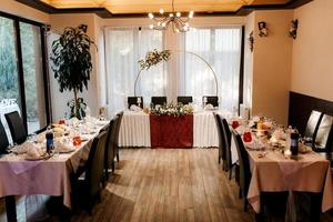 le présidium des jeunes mariés dans la salle de banquet du restaurant est décoré de bougies et de plantes vertes photo