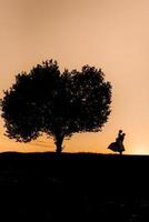 silhouettes d'un jeune couple heureux et fille sur fond de coucher de soleil orange photo