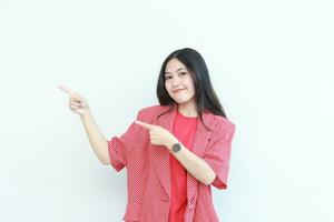 portrait de magnifique asiatique femme portant rouge tenue montrer du doigt à le côté pour copie espace photo