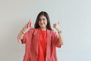 portrait de magnifique asiatique femme portant rouge tenue avec se mettre d'accord ou D'accord geste tandis que souriant pour célébrer Indonésie indépendance journée photo