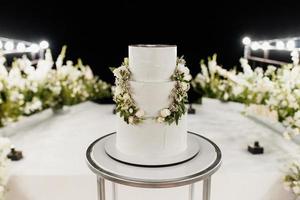 gâteau blanc de mariage sur un stand élevé près du podium blanc photo