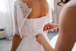 habiller la mariée dans une robe de mariée avec corset et laçage photo