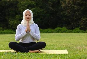 jeune femme musulmane asiatique assise sur l'herbe, profitant de la méditation photo