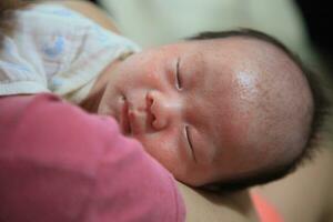 soumissionner des moments asiatique bébé en train de dormir pacifiquement dans les mères bras photo