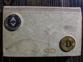 Bitcoin et ethereum sur un vieux livre posé sur une table en bois.nouvelle monnaie virtuelle photo