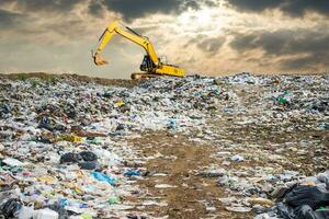 des ordures déverser pile dans poubelle déverser ou décharge, rétrocaveuse et un camion est dumping le gabage de municipal, poubelle déverser pile et foncé ciel Contexte ,pollution concept photo