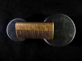 peigne en bois et pots de cire à barbe et moustache sur fond noir photo