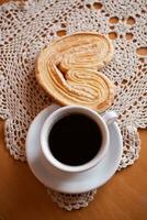 blanc tasse de noir café et une sucré de beurre biscuit sur le table photo