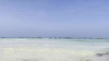 bateaux de pêche dans l'eau turquoise sur une plage de sable blanc poussé par les vagues. zanzibar, tfnzanie, océan indien