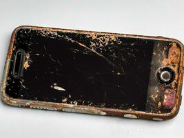 vieux mobile téléphone avec cassé écran sur le béton sol photo