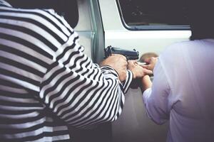 voiture voleurs tenir une pistolet à Rob une voiture de une femme qui possède il. fermer photo. Assurance concept. protection de la vie et propriété photo