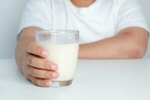 graisse garçon en portant une plein verre de lait. les enfants sont en buvant lait. le concept de en bonne santé en mangeant il est bénéfique pour le croissance de les enfants. photo