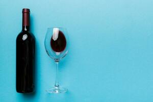 verre de rouge du vin et une bouteille sur coloré tableau. plat poser, Haut vue avec copie espace photo