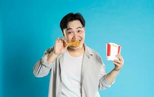 portrait de asiatique homme en mangeant vite nourriture sur bleu Contexte photo