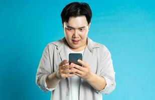 image de asiatique homme en utilisant téléphone sur bleu Contexte photo