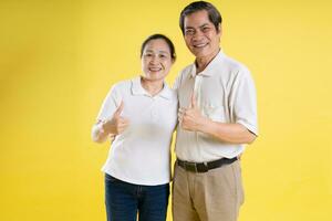 portrait de milieu vieilli asiatique couple posant sur Jaune Contexte photo