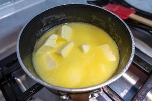 Bâton de beurre fondant dans une casserole sur une cuisinière à gaz photo