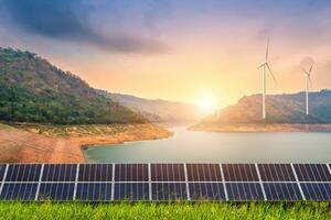 solaire panneaux avec vent turbines contre vue de le réservoir et montanis paysage contre pendant ciel coucher de soleil, alternative énergie concept. photo