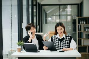 deux asiatique femme d'affaires et homme discuter investissement projet travail et Planification stratégie avec tablette portable ordinateur dans bureau. photo