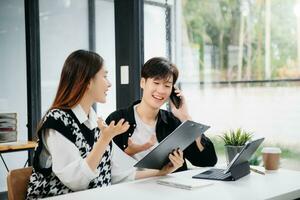 deux asiatique femme d'affaires et homme discuter investissement projet travail et Planification stratégie avec tablette portable ordinateur dans bureau. photo