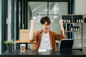 asiatique homme d'affaire sont Enchanté et content avec le travail elles ou ils faire sur leur tablette, portable et prise Remarques à le bureau. photo