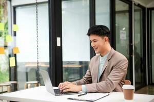 jeune homme d'affaires travaillant au bureau avec ordinateur portable, tablette et prenant des notes sur le papier. photo