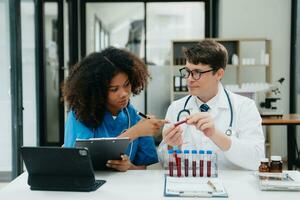 deux scientifique ou médical technicien fonctionnement, ayant une médical discuter réunion avec un asiatique Sénior femelle scientifique superviseur dans le laboratoire avec en ligne en lisant, tester échantillons photo