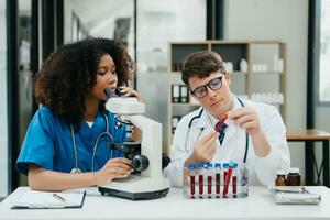 deux scientifique ou médical technicien fonctionnement, ayant une médical discuter réunion avec un asiatique Sénior femelle scientifique superviseur dans le laboratoire avec en ligne en lisant, tester échantillons photo