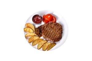 délicieux steak de boeuf juteux avec pommes de terre au four et sauces sur un plat blanc photo