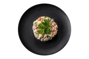 délicieuse salade d'olivier frais avec saucisse, œuf, concombre, pois verts, carottes et mayonnaise photo