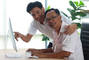 le fils apprend à son père à utiliser l'ordinateur photo