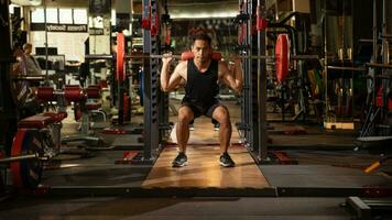 une portrait de une Masculin haltérophile dans noir tenue de sport. il Est-ce que haltère aptitude faire des exercices dans le moderne salle de sport. musculation, Puissance levage entraînement, des sports amoureux photo