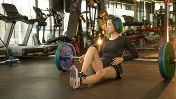 jolie femme dans tenue de sport fatigué après levage haltère dans une salle de sport. photo