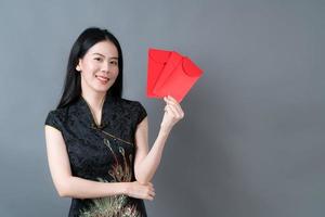 une femme asiatique porte une robe traditionnelle chinoise avec une enveloppe rouge ou un paquet rouge photo