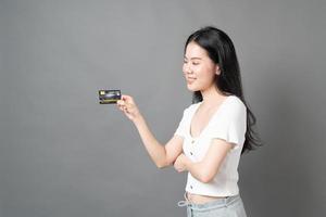 femme asiatique avec un visage heureux et présentant une carte de crédit en main montrant la confiance pour effectuer le paiement photo