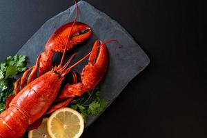 homard rouge aux légumes et citron sur plaque d'ardoise noire photo