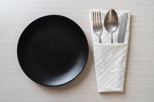 assiette ou plat vide avec couteau, fourchette et cuillère sur fond de carreaux de bois photo