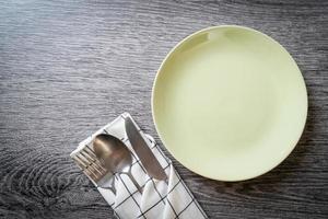assiette ou plat vide avec couteau, fourchette et cuillère sur fond de carreaux de bois photo