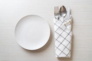 assiette ou plat vide avec couteau, fourchette et cuillère sur fond de carreaux de bois photo