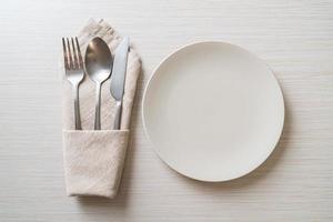 assiette ou plat vide avec couteau, fourchette et cuillère sur fond de carreaux de bois photo